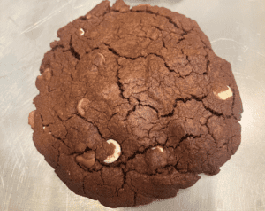 A chocolate cookie with white chips on top of it.