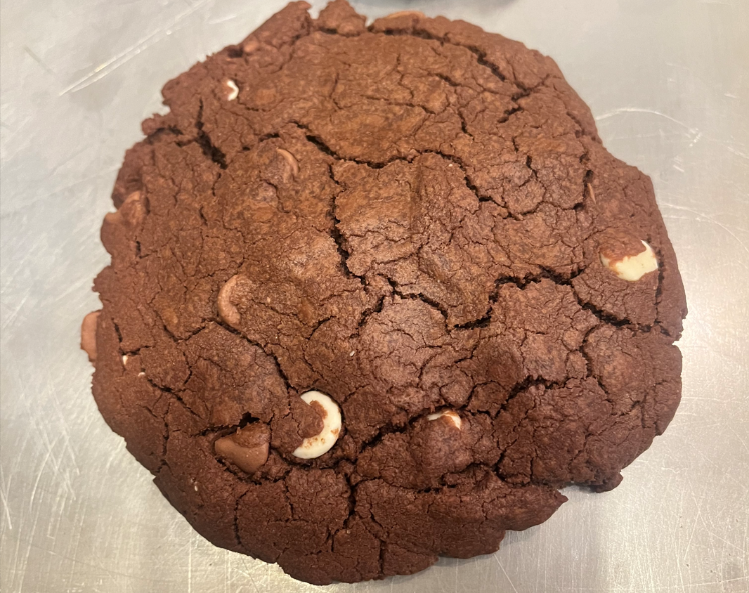 A chocolate cookie with white chips on top of it.