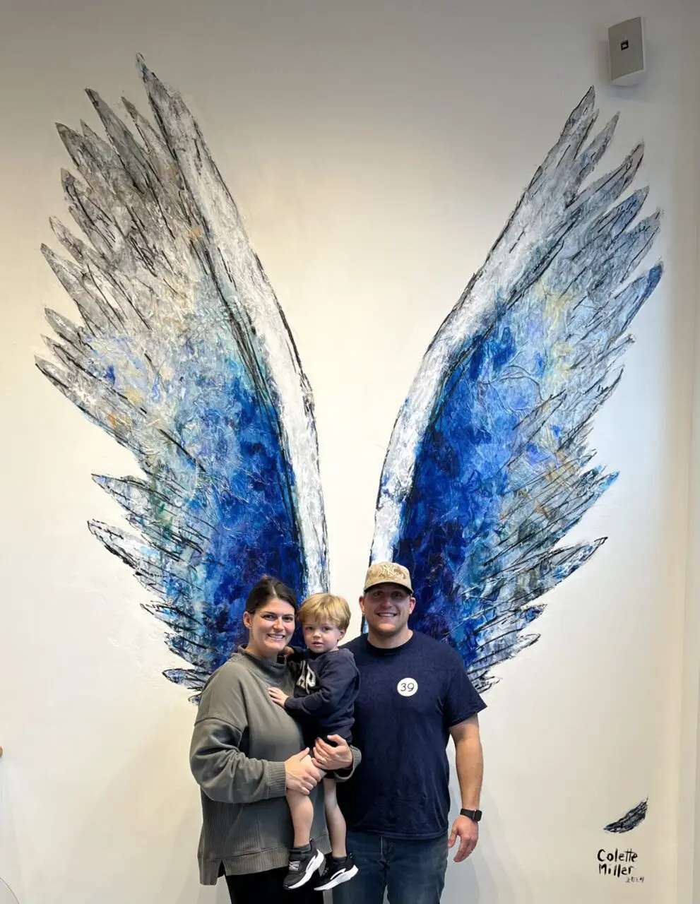 A family posing in front of an angel wing.